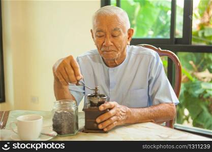 Asian senior man with vintage coffee grinder