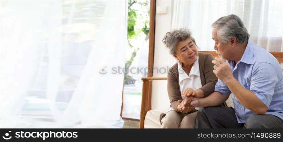 Asian senior retired couple holding hands and take care together at home, Alzheimer disease or suffering with dementia concept