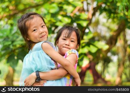Asian sister carrying her little girl in a summer green park.