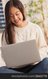 Asian smiling woman is working with notebook at home