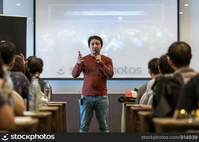 Asian Speaker with casual suit on the stage over the presentation screen in the business or education seminar