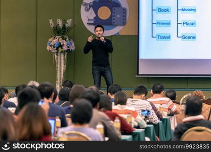 Asian Speaker with casual suit on the stage present the screen in the conference hall or seminar meeting, business and education concept