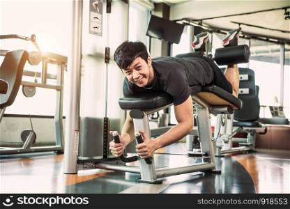 Asian sport man stretching and lifting weight by two legs when facing down for stretching muscle at fitness gym at condominium background. Sport and People lifestyles concept.