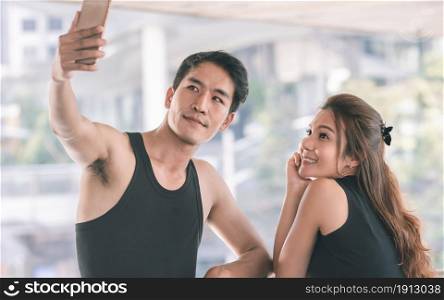 Asian sportive man and woman using mobile phone to take selfie. after doing exercise. Sport and Technology Concept.