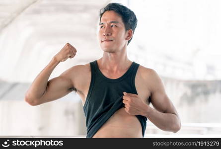 Asian sportive man showing his shape after doing exercise outdoor