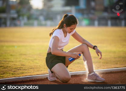 Asian Sports women using freezing spray for treating injured sportwomen&rsquo;s knee and leg after run