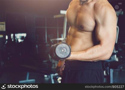Asian sportsman raise dumbbell with muscular building at gym.