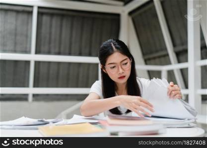 Asian student women reading books in library at university. Young undergraduate girl do homework, read textbook, study hard for knowledge and education on lecture desk at college campus.