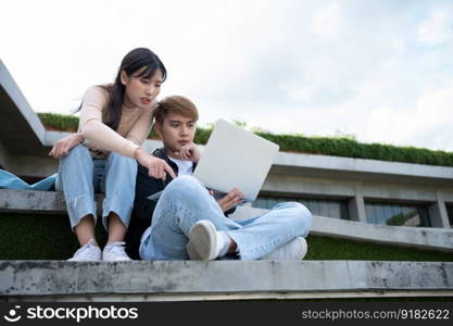 Asian students sitting on steps and use computer laptops to discuss before exams, Student lifestyle at university. Group of student do a project together