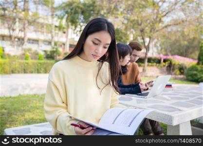 Asian students use notebook computers and tablet to work and study online in garden at home during the coronavirus epidemic and quarantine at home