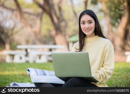Asian students use notebook computers and tablet to work and study online in garden at home during the coronavirus epidemic and quarantine at home