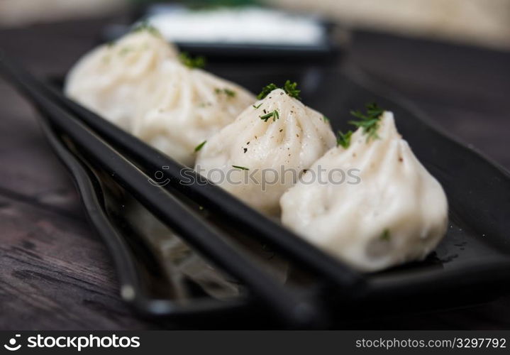 Asian-style meat dumplings with cream sauce on wooden table