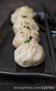 Asian-style meat dumplings with cream sauce on wooden table