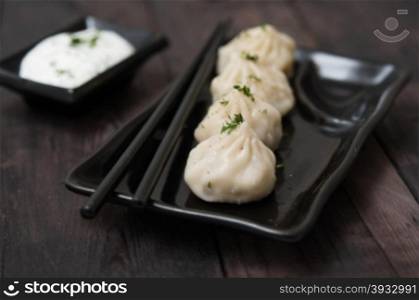 Asian-style meat dumplings with cream sauce on wooden table
