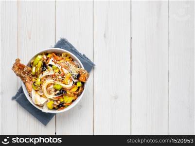 Asian style noodles with vegetables, chicken and teriyaki sauce. Top view, noodle bowl on a white wooden background with copy space. Lunch, noodles with chicken, vegetables, spices and micro-greens. Asian style noodles with vegetables, chicken and teriyaki sauce.