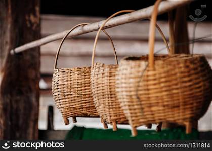 Asian style Wicker bamboo rattan basket with wooden handle hanging on bamboo stick in farmer house