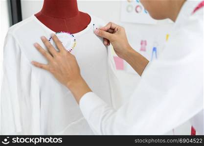 Asian tailor adjusts garment design on mannequin in workshop make a little adjustment to her work on model in the studio