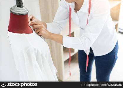 Asian tailor adjusts garment design on mannequin in workshop make a little adjustment to her work on model in the studio