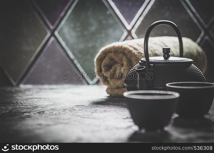 Asian tea set and spa settings on stone background near the old window. Natural spa treatment and relaxation concept. Tea and SPA composition. Natural cosmetics and wellness concept.