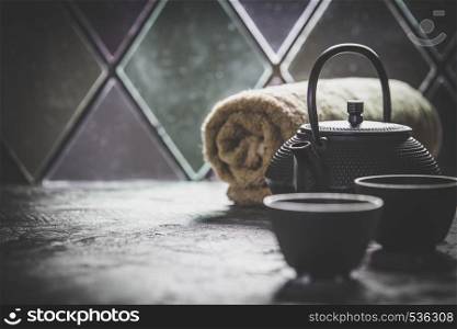 Asian tea set and spa settings on stone background near the old window. Natural spa treatment and relaxation concept. Tea and SPA composition. Natural cosmetics and wellness concept.