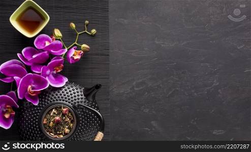 asian tea set with orchid flower dried tea ingredient black place mat