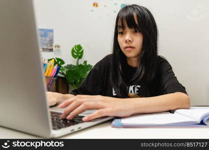 Asian teen girl use computer laptop technology internet online research information social network and education homework on table.