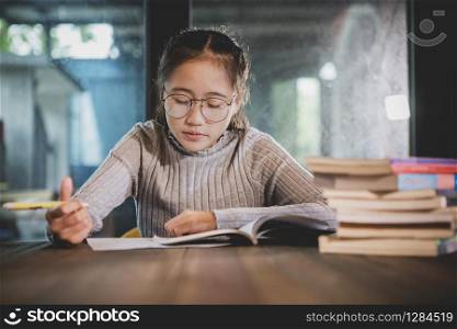 asian teenager doing school home work in library room