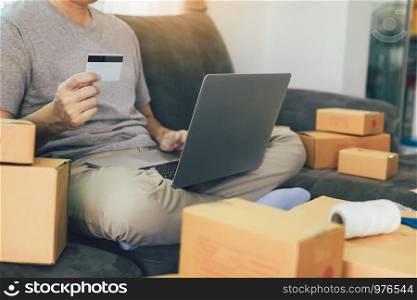 Asian teenager holds a credit card and is using a laptop computer shopping online concept.