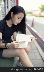 asian teenager reading book school street side