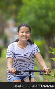 asian teenager riding bicycle in natural green park