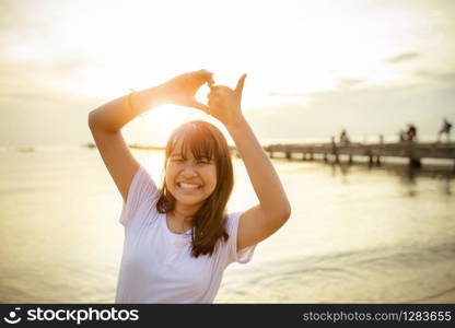 asian teenager sign heart shape by hand with beautiful sunset sky background