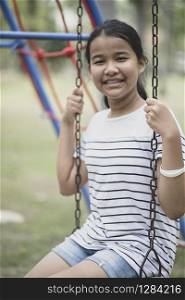 asian teenager sitting on swing in public park toothy smiling face happiness emotion