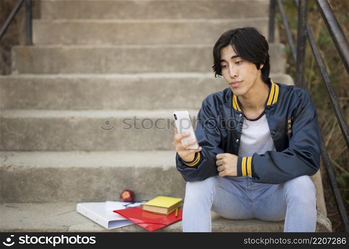 asian teenager sitting with phone stairs
