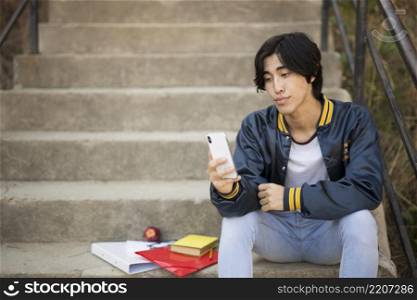 asian teenager sitting with phone stairs