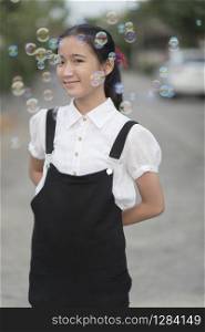 asian teenager smiling face relaxing outdoor with soap bubble floating