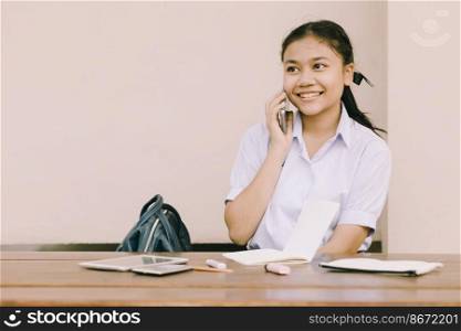 Asian Thai cute girl teen student school uniform using phone calling happy smile.