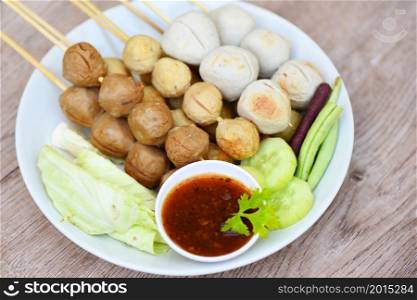 Asian Thai food grilled meatballs fishball and porkball with spicy sauce, Meatballs on skewers on white plate and fresh vegetables cabbage yard long bean cucumber