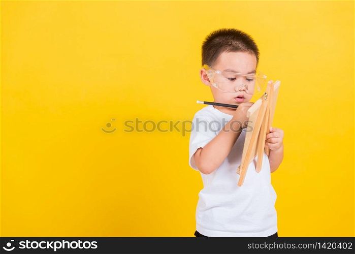 Asian Thai happy portrait cute little cheerful child boy smile are drawing on blackboard and looking the board, studio shot isolated on yellow background with copy space