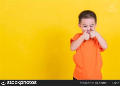 Asian Thai happy portrait cute little cheerful child boy wearing an orange t-shirt looking camera, studio shot isolated on yellow background with copy space