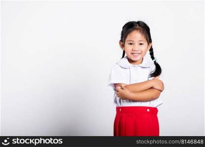 Asian toddler smile happy wearing student thai uniform red skirt stand with arms folded in studio shot isolated on white background, Portrait little children girl preschool crossed arm, Back to school
