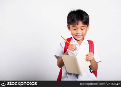 Asian toddler smiling happy wear student thai uniform red pants holding pencil for writers notebook in studio shot isolated on white background, Portrait little children boy preschool, Back to school