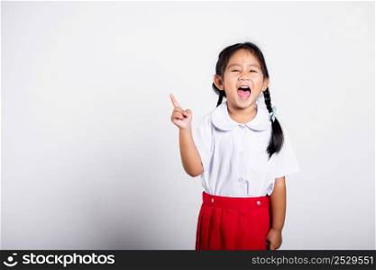 Asian toddler smiling happy wear student thai uniform red skirt keeps pointing finger at copy space in studio shot isolated on white background, Portrait little children girl preschool, Back to school