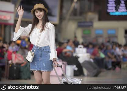 Asian tourist woman smile waving a hand greeting on the train station
