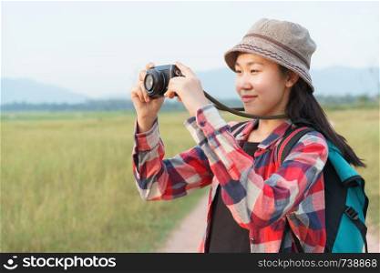 Asian tourist woman taking photo by digital camera on nature mountain view. A young girl is traveling on summer vacation.
