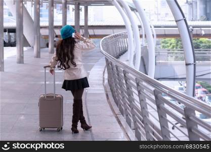 Asian Travel woman wearing sweater coat, blue yarn hat with luggage, calling phone at shopping business street background for traveler vacation tourist concept