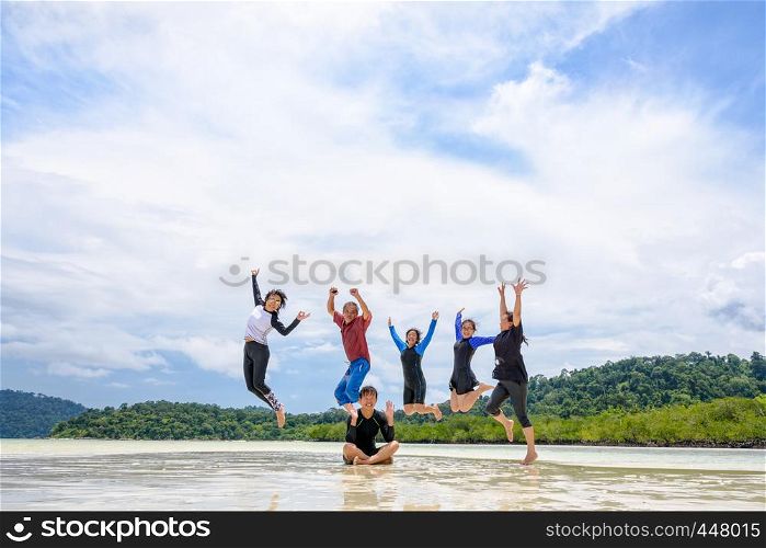 Asian traveler group adult and teens are family, Happy life enjoy by play jumping together at the beach on blue sky background, vacation in summer holiday at Ko Lipe and Ra Wi island, Tarutao, Thailand. Happy family jumping together on the beach, Thailand