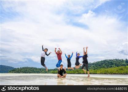 Asian traveler group adult and teens are family, Happy life enjoy by play jumping together at the beach on blue sky background, vacation in summer holiday at Ko Lipe and Ra Wi island, Tarutao, Thailand. Happy family jumping together on the beach, Thailand
