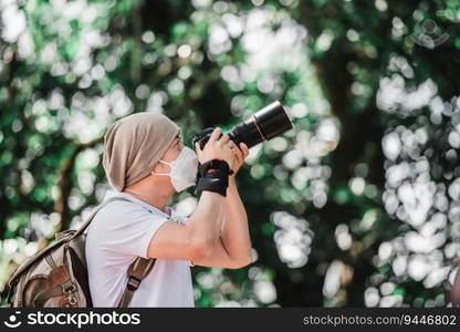 Asian traveler man with backpack taking a photo in the park with copy space. Travel photographer. Vocation and holiday concept.