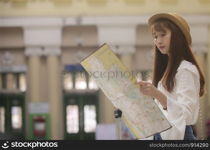 Asian traveler woman looking map at train station