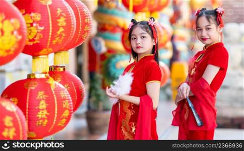 Asian Two girl wearing red traditional Chinese cheongsam decoration holding a Chinese Fanning and lanterns with the Chinese text Blessings written on it Is a Fortune blessing for Chinese New Year